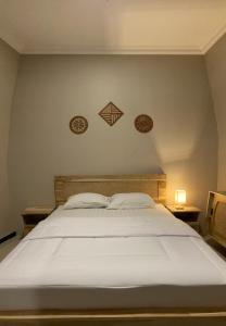 Pesona Guesthouse Syariah Malang في Kotalama: سرير أبيض كبير مع طبقين على الحائط