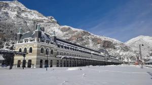 a large building with snow covered mountains in the background at La Moleta AVAIRENT Canfranc Estación in Canfranc-Estación