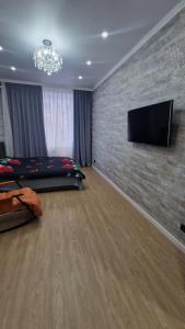 a bedroom with a bed and a flat screen tv on a brick wall at Апартаменты в ЖК Мерей in Karagandy