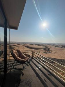 a wicker chair sitting on a porch looking out over the desert at Oman desert private camp in Shāhiq