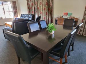 uma sala de jantar com uma mesa e cadeiras de couro em 4bed 2bath house 5 mins walk to Palms & Golf club em Christchurch