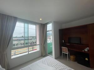 um quarto de hotel com uma cama e uma grande janela em Chalong inn Phuket em Chalong