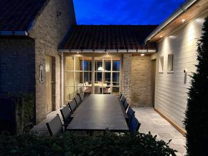 a patio with a long table and chairs at night at De Landsgenieter in Nieuwpoort