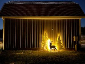 a deer walking in front of a building with christmas trees at Ny lägenhet i Vesene in Ljung