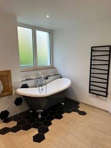 een badkamer met een bad in een kamer met ramen bij Gîte 8 personnes in Bellenot-sous-Pouilly