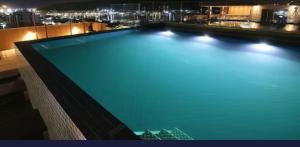 a large swimming pool on top of a building at night at Hotel Samba Cabo Frio Flat in Cabo Frio