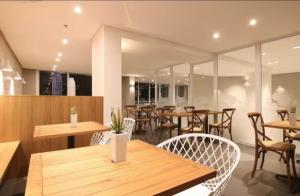 un restaurante con mesas y sillas de madera y ventanas en Hotel Samba Cabo Frio Flat en Cabo Frío