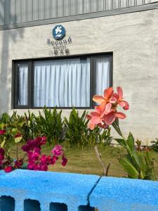 un edificio con una ventana y flores delante de él en Second Hostel, en Xiaoliuqiu