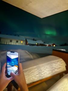a person holding a cell phone in front of a bed at Lys og moderne leilighet rett ved skiløypa på Nordseter - Kort vei til Sjusjøen, Lillehammer og Hafjell - Dyr ikke tillatt in Nordseter