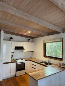 a kitchen with white appliances and a wooden ceiling at Ariel's Beach House in Rye