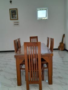een houten eettafel met stoelen en een gitaar bij Abhishek Villa in Kekanadura
