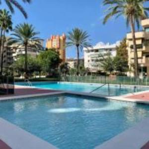 a large swimming pool with palm trees in a city at Primera Linea del Mar - Acceso Directo Playa Carihuela in Torremolinos