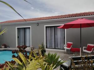 een huis met een zwembad en een rode parasol bij Mi Amor self catering apartment in Kaapstad