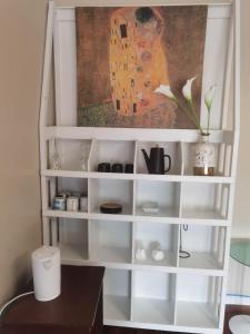 a white book shelf with a painting on the wall at Mt Eden Master Suite RM1 in Auckland