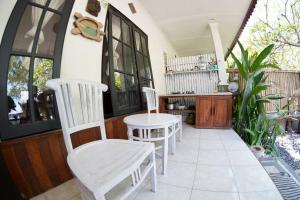 Un porche con sillas blancas y una mesa. en Jepun Villas 11 - One Bedroom with kitchen, en Uluwatu