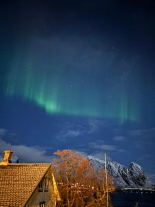 an aurora in the sky above a house at Buodden Rorbuer - Fisherman Cabins Sørvågen in Sørvågen
