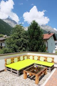 a patio with a bench and a table and chairs at Hellweger Apartments in Anterselva di Mezzo