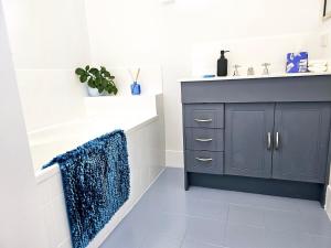 La salle de bains est pourvue d'un lavabo et d'une armoire bleue. dans l'établissement Bakers Sea Breeze Escape, à North Ward