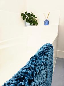 un tapis bleu tricoté sur un étage à côté d'une plante dans l'établissement Bakers Sea Breeze Escape, à North Ward