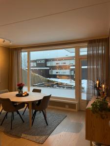 a living room with a table and a large window at Cosy and centrally located apartment in Tromsø