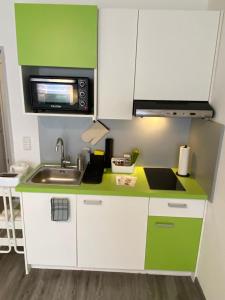 una pequeña cocina con fregadero y microondas en Apartment Kompakt 24/7, en Kassel