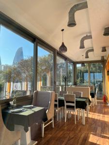 a restaurant with tables and chairs and large windows at La Casa Old City Hotel in Baku