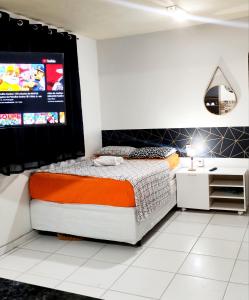a bedroom with a bed and a flat screen tv at Loft Av Vitória prox a Faesa in Vitória