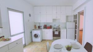 une cuisine avec des placards blancs, une table et un lave-linge dans l'établissement STAY Virtuoso Apartment Nicosia, à Nicosie