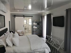 a bedroom with a white bed and a television at Mi Amor self catering apartment in Cape Town