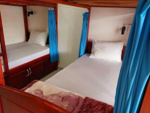 twee bedden in een kleine kamer met blauwe gordijnen bij Cam Ly Homestay in Da Lat