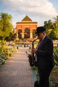 Um homem a tocar saxofone em frente a um edifício. em Nomadz Palace em Marraquexe