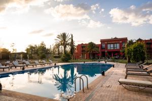 uma grande piscina com cadeiras e um edifício em Nomadz Palace em Marrakech