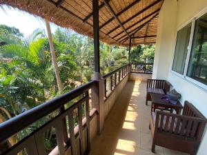 a balcony of a house with a table and benches at Good Time Sports Village Koh Mak in Ko Mak