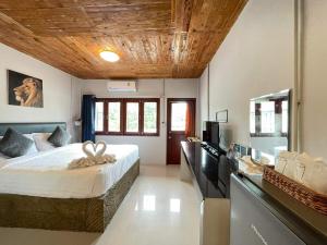 a bedroom with a large bed with a wooden ceiling at MOOK BOONCHU HOTEL in Koh Mook
