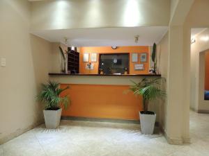 a lobby with two potted plants in front of a counter at Hotel Buenos Aires in Salta