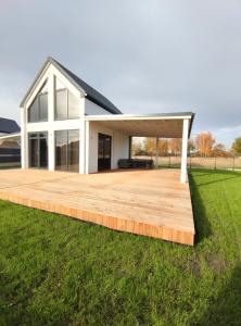 een houten terras voor een huis bij Ferienhaus Mila 70qm bis 5 Gäste mit Sauna, Whirlpool in der Hauptsaison, 75qm Terrasse und eingezäunten Garten Haustiere willkommen in Sierosław