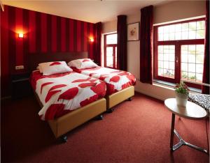 1 dormitorio con 1 cama grande con mantas rojas y blancas en Herberg St. Brigida, en Noorbeek