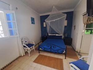 a bedroom with a blue bed with a canopy at Villa La Palmeraie in Oualidia