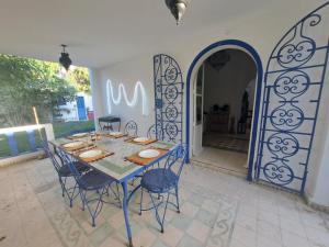 una mesa azul y sillas en una habitación con puerta en Villa La Palmeraie, en Oualidia