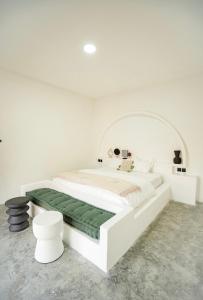 een witte slaapkamer met een wit bed en een groene deken bij Hacienda Villa Watukarung in Watukarung