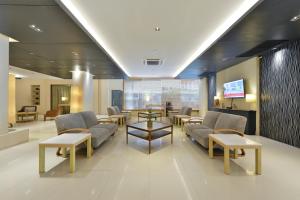 a hospital lobby with couches and tables and a tv at Royal View Resort - Rang Nam in Bangkok