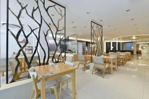 a restaurant with tables and chairs and a tree mural at Royal View Resort - Rang Nam in Bangkok