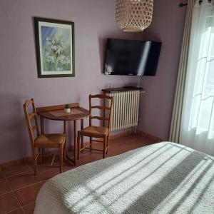 - une chambre avec une table, des chaises et une télévision dans l'établissement la chambre de l'auxineill, à Castelnou