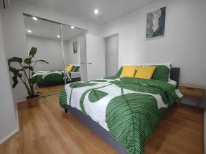 Un dormitorio con una cama verde y blanca con almohadas amarillas en Resort style 1 or 2 bedroom with pool and free parking en Hornsby