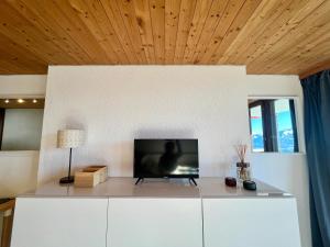 a living room with a tv on a white wall at THE ALPINE STUDIO on the ski slopes - by the lake - Alpe des Chaux - Gryon in Gryon