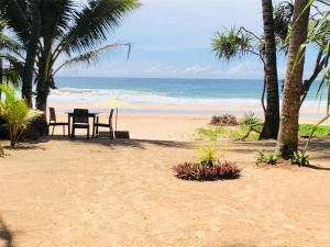 een tafel en stoelen op een strand met uitzicht op de oceaan bij Mandy House in Habaraduwa Central