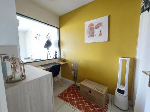 a kitchen with a yellow wall with a box on the floor at Studio sur les rives d'allier in Moulins