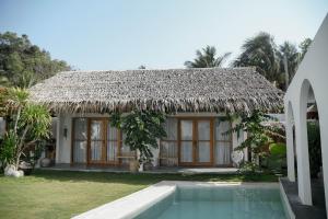 een huis met een rieten dak en een zwembad bij Hacienda Villa Watukarung in Watukarung