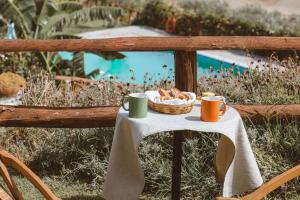 una mesa con una cesta de pan y tazas de café en Calàmi - Villa Romeo - Private Apartments with Pool, Seaview & Olive Grove en Santa Caterina Dello Ionio Marina