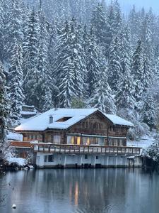 una cabaña de madera en la nieve junto a un lago en Chalet Familial Sublime en Crans-Montana